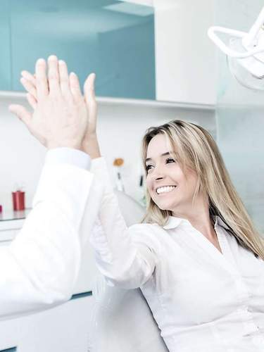 Glückliche Patientin gibt ihrem Zahnarzt nach der Behandlung ein High Five 