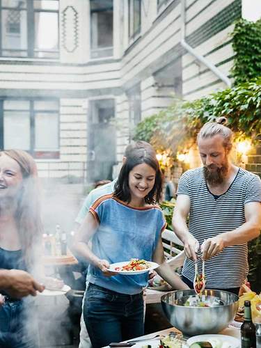 Junge Menschen grillen unbeschwert zusammen in einem Hinterhof