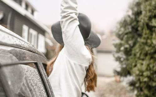 Eine Frau lehnt sich aus dem offenen Beifahrerfenster hinaus und streckt ihren Arm nach oben.